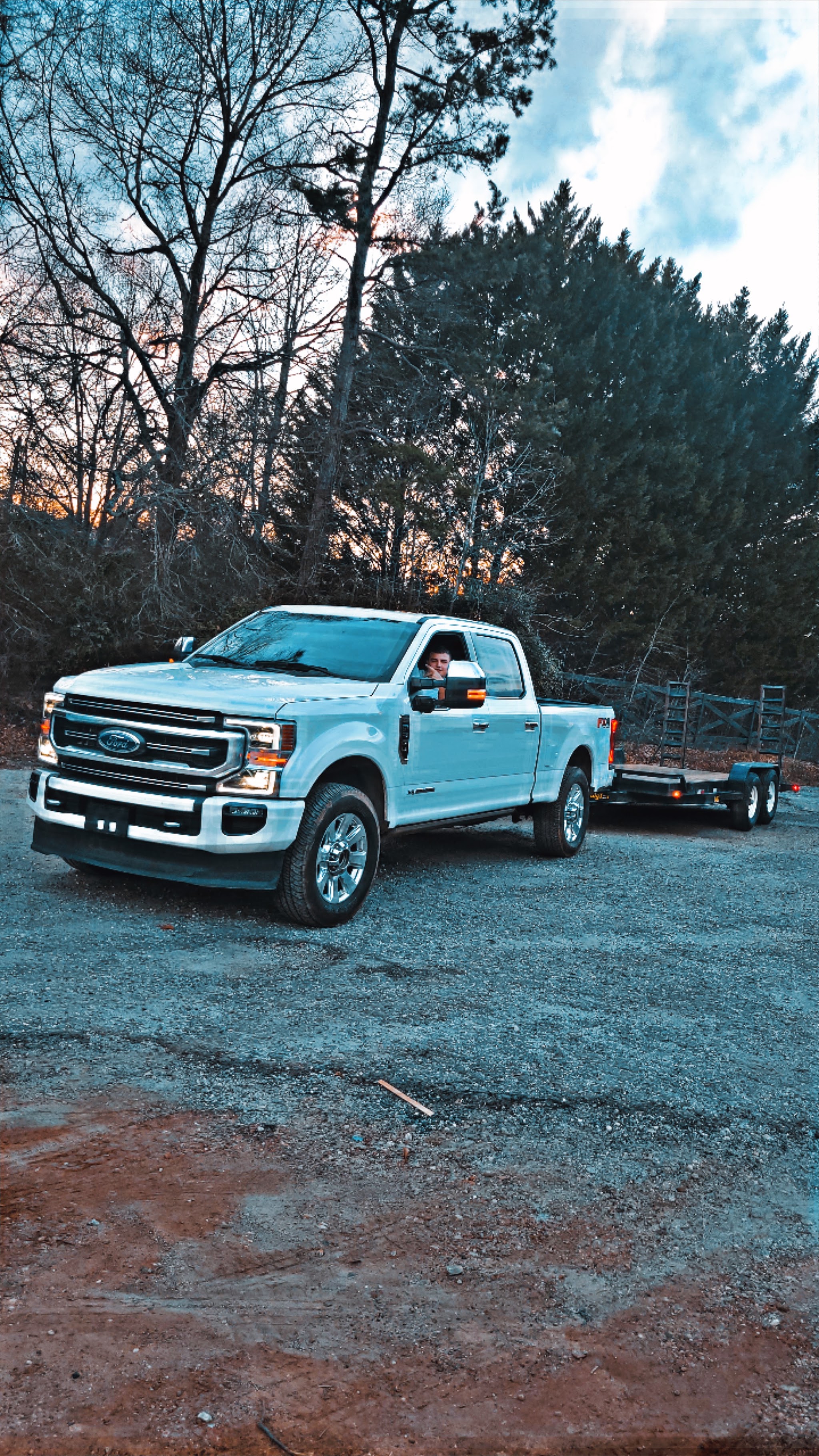 Our white Ford service truck pulling an equipment trailer at dusk